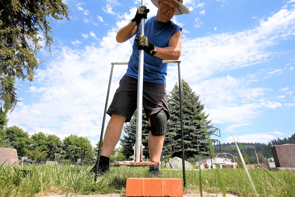 Mike Kopf taps a paver in place at what was an unmarked gravesite on Friday at St. Thomas Cemetery.
