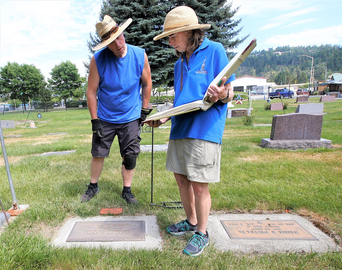 Mike Kopf and Tina Johnson look over burial site records for St. Thomas Cemetery on Friday.
