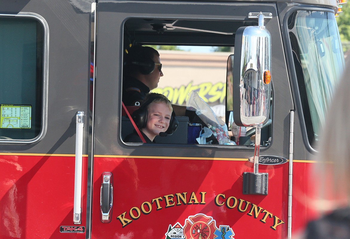 Troy Carr, 8, smiles at the crowd as his dad, firefighter and EMT Taylor Carr, drives a Kootenai County Fire and Rescue truck in the Post Falls Festival Parade on Saturday morning.