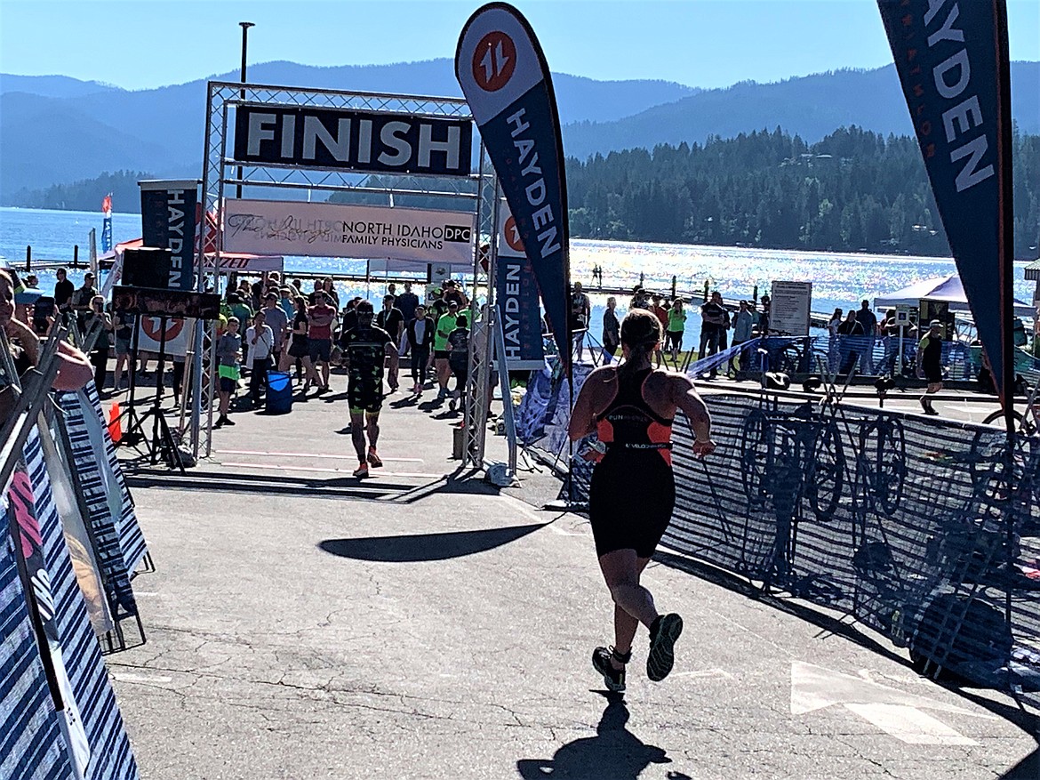 A runner heads to the Hayden Triathlon finish area, with Hayden Lake in the background on Saturday.