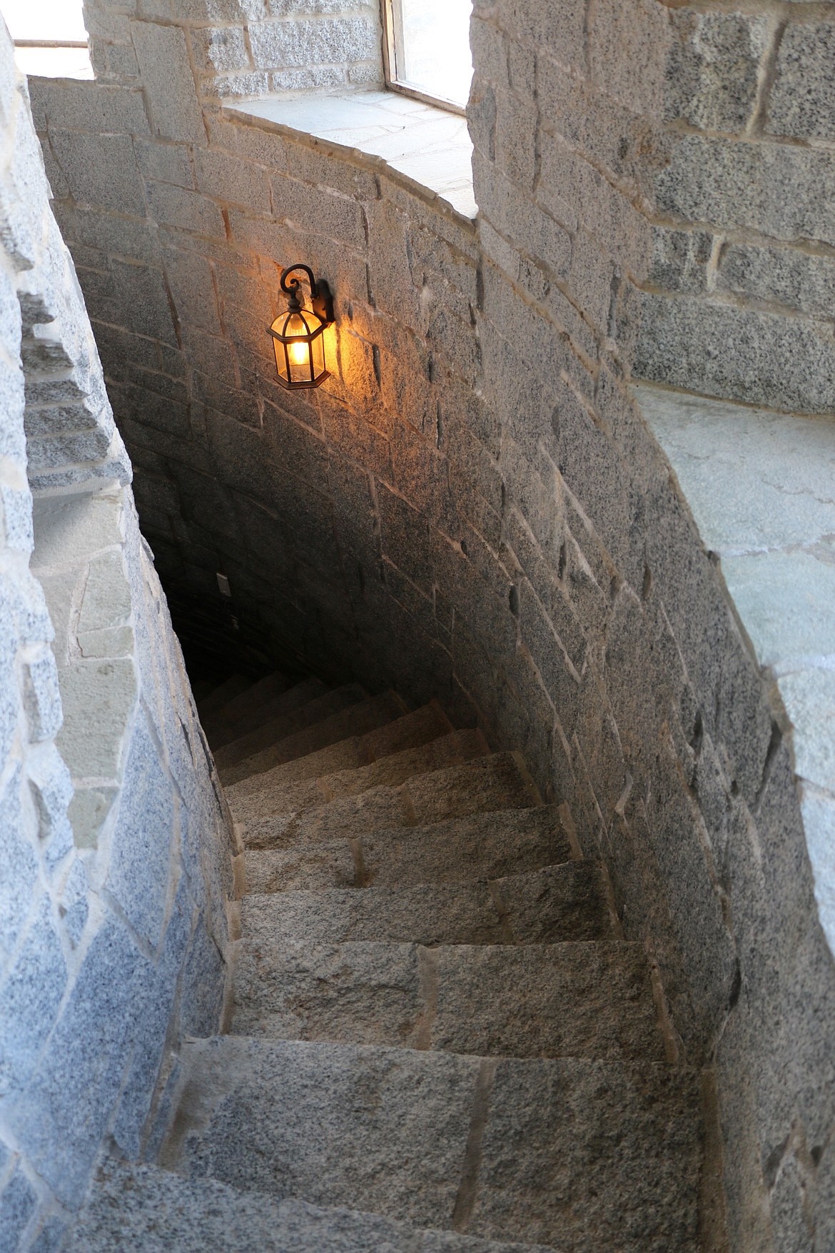 A curved stone stairway leading down to the tunnel entrance of the castle.