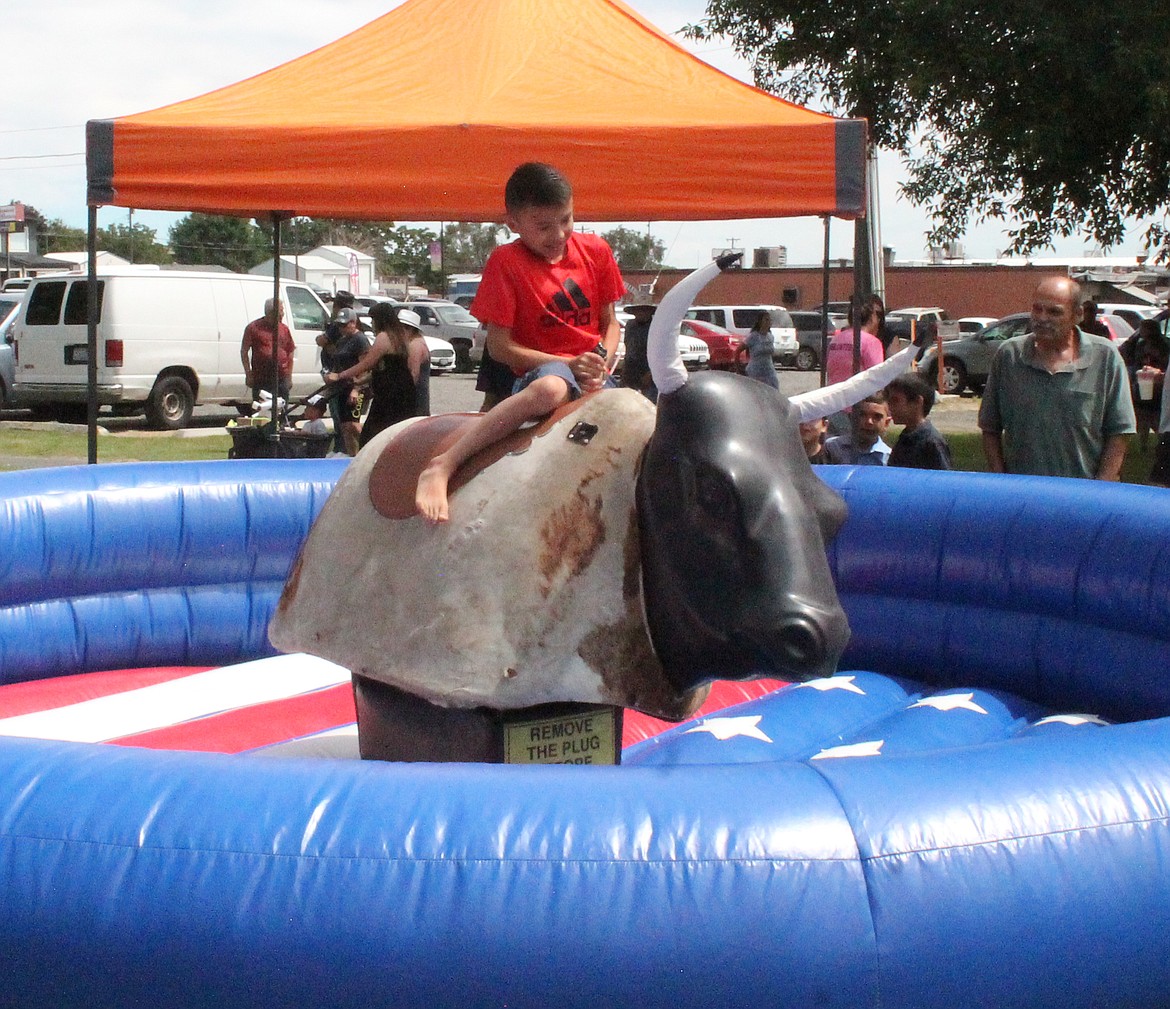 A young buckaroo stays in his seat on a mechanical bull at Summerfest Saturday in Royal City.