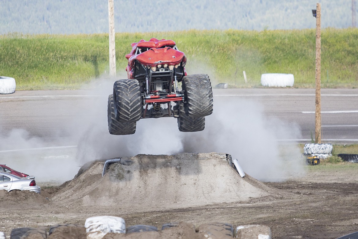 Spitfire, a dragon themed truck, jumps off a ramp made of demolished cars.