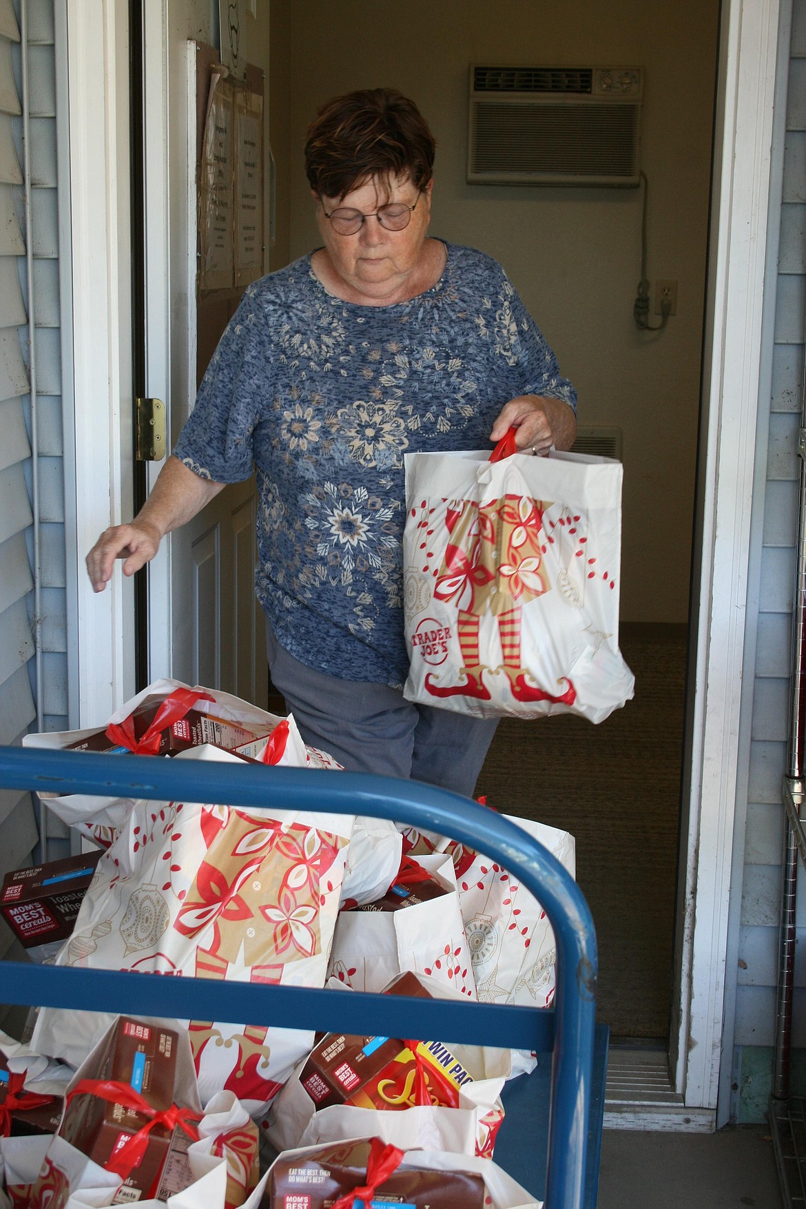 Othello Food Bank Director Sharon Mobley adds sacks filled with food to a cart, preparing them for donation to clients in Hatton.