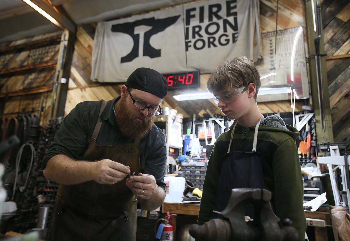 Fire Iron Forge owner and blacksmith David Walker inspects a hook his student Leo Adira, 12, is working on during a session at the forge.
