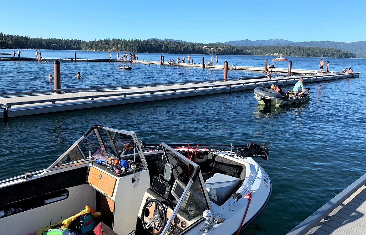 A boat is tied to the dock at Honeysuckle Beach, while another heads out to Hayden Lake, next to the swimming area on Wednesday.