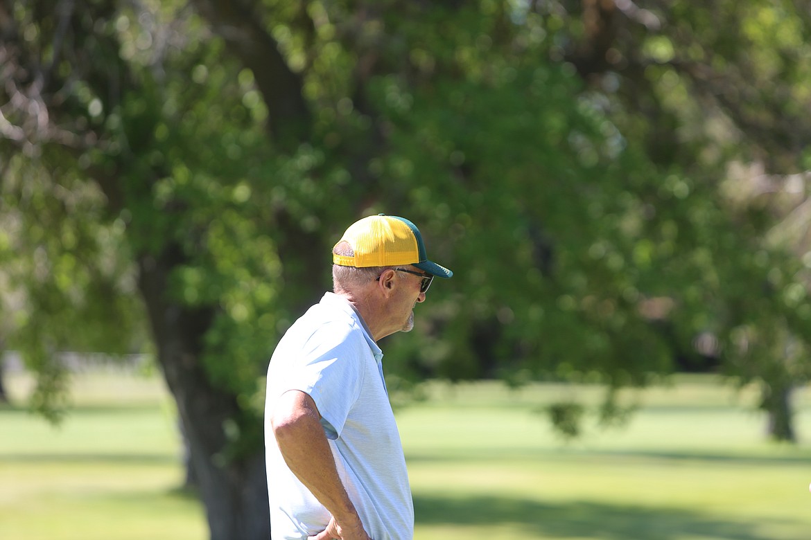Looking on at the seventh hole, this golfer dons a yellow and black-colored hat.
