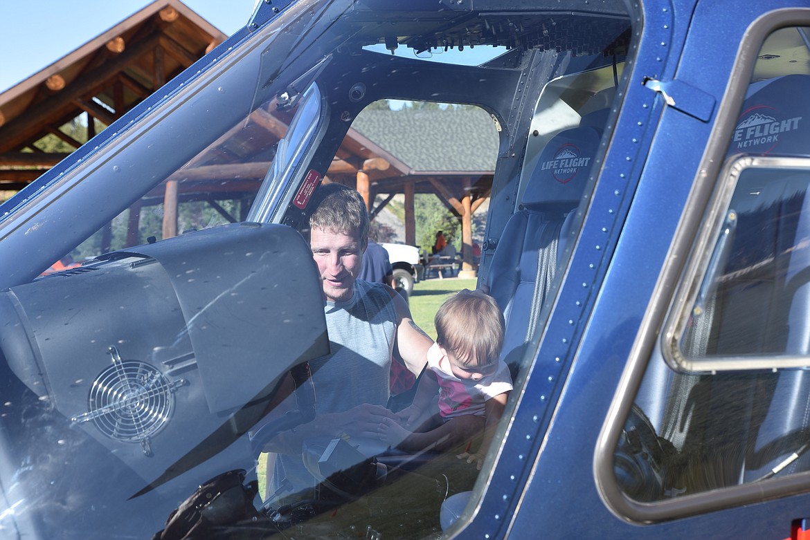 Seth Power, of Libby, helps his child get the inside view of a Life Flight helicopter at last Thursday’s water safety presentation at Riverside Park. (Scott Shindledecker/The Western News)