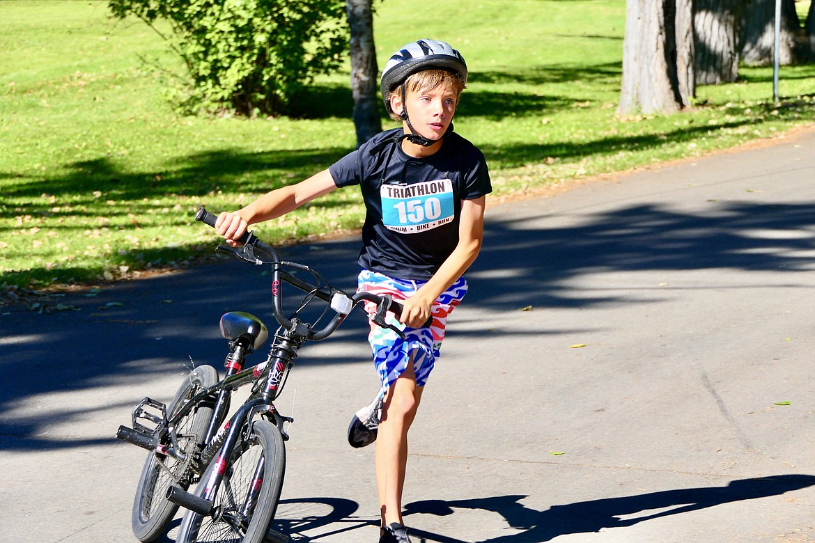 Kamden Campbell, 9, of Kalispell, transitions from biking to running during the Logan Health Kids Triathlon at Woodland Park in Kalispell on Saturday, July 16. (Matt Baldwin/Daily Inter Lake)