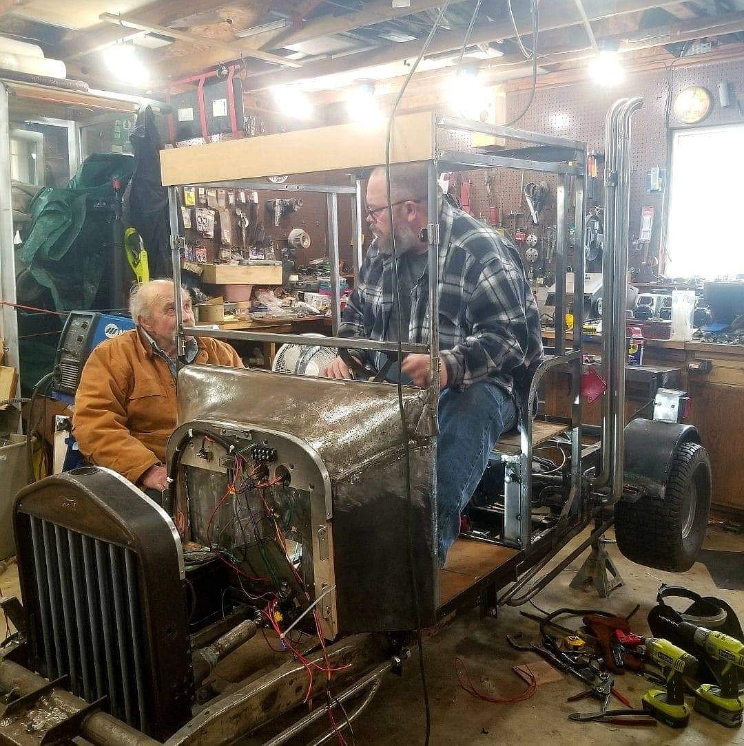 Nye Evert Brown Sr., left, and Nye Evert Brown Jr., right, work on the 1926 Ford golf cart.