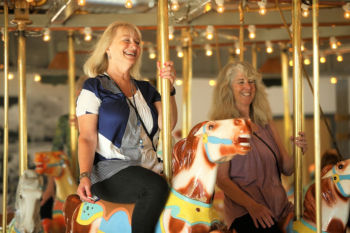 Becca Lines, left, and Sue Field with the 3Cs ride the Coeur d'Alene Carousel on Tuesday.