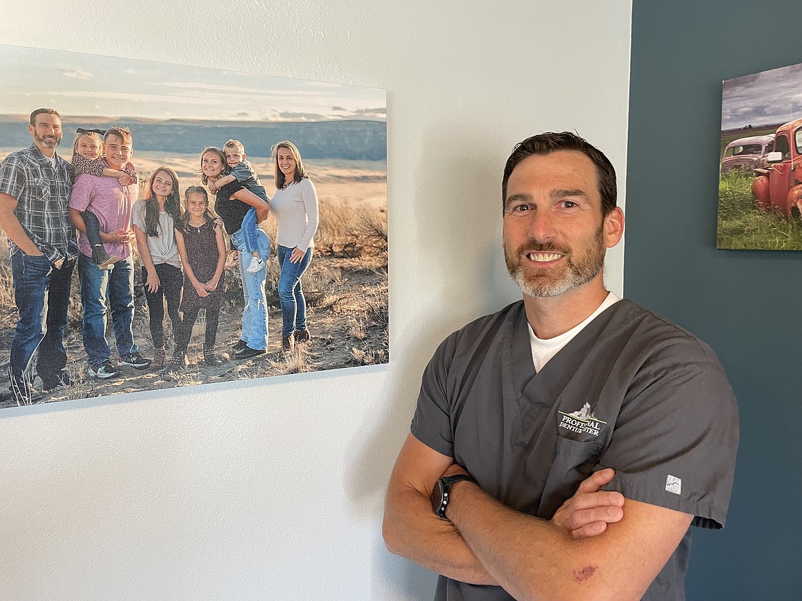 Jon Dickson, a dentist and oral surgeon who specializes in making dentures, stands in the lobby of his new Moses Lake clinic next to a photo of himself with his wife and their six children. Dickson and his partner Walter Walden, who have had a clinic in Wenatchee for a number of years, have just opened a Moses Lake clinic.