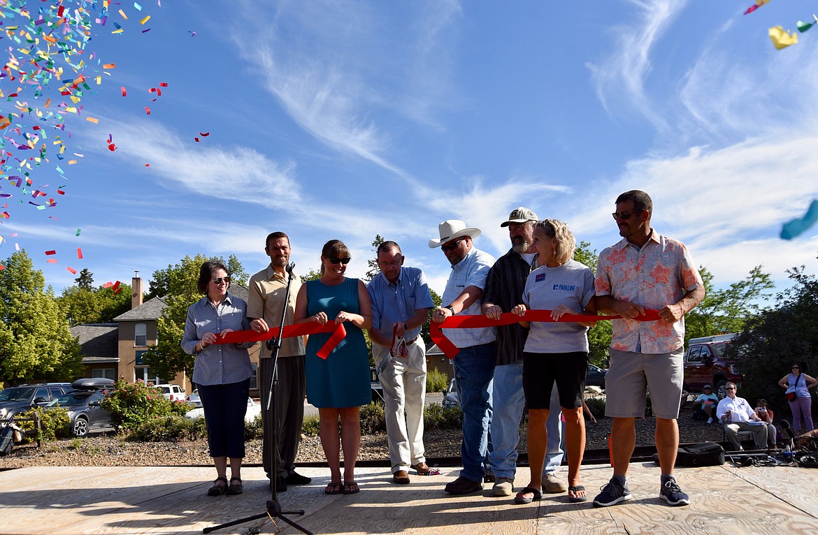 As the crowd begins to shoot off confetti, Mayor Mark Johnson, center, cuts the ribbon held by Kalispell City Council members Thursday officially opening the Parkline Trail. (Heidi Desch/Daily Inter Lake)