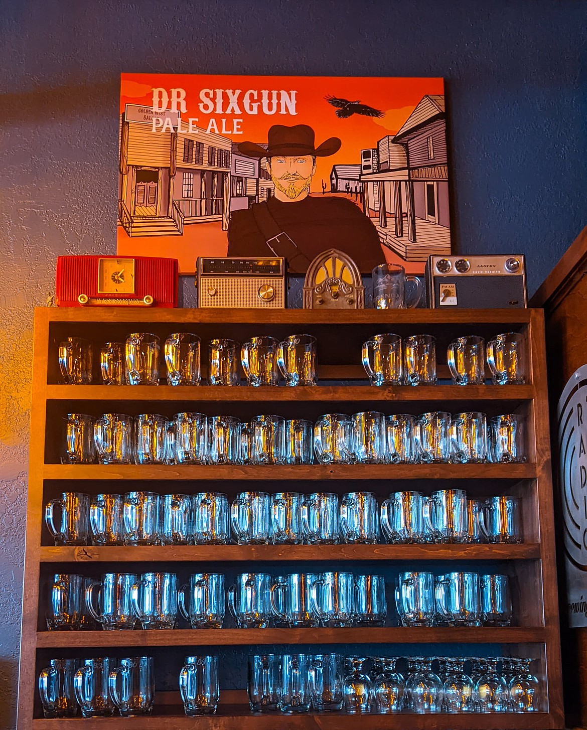 Radio Brewing Company caters to its community by providing a Mug Club for those who love to satiate their thirst with their specialty brewed beer. In the background, the Dr. Sixgun Pale Ale painting was done by the owner, Ashley Mehaffie and was one of the first beers brewed for the company.
