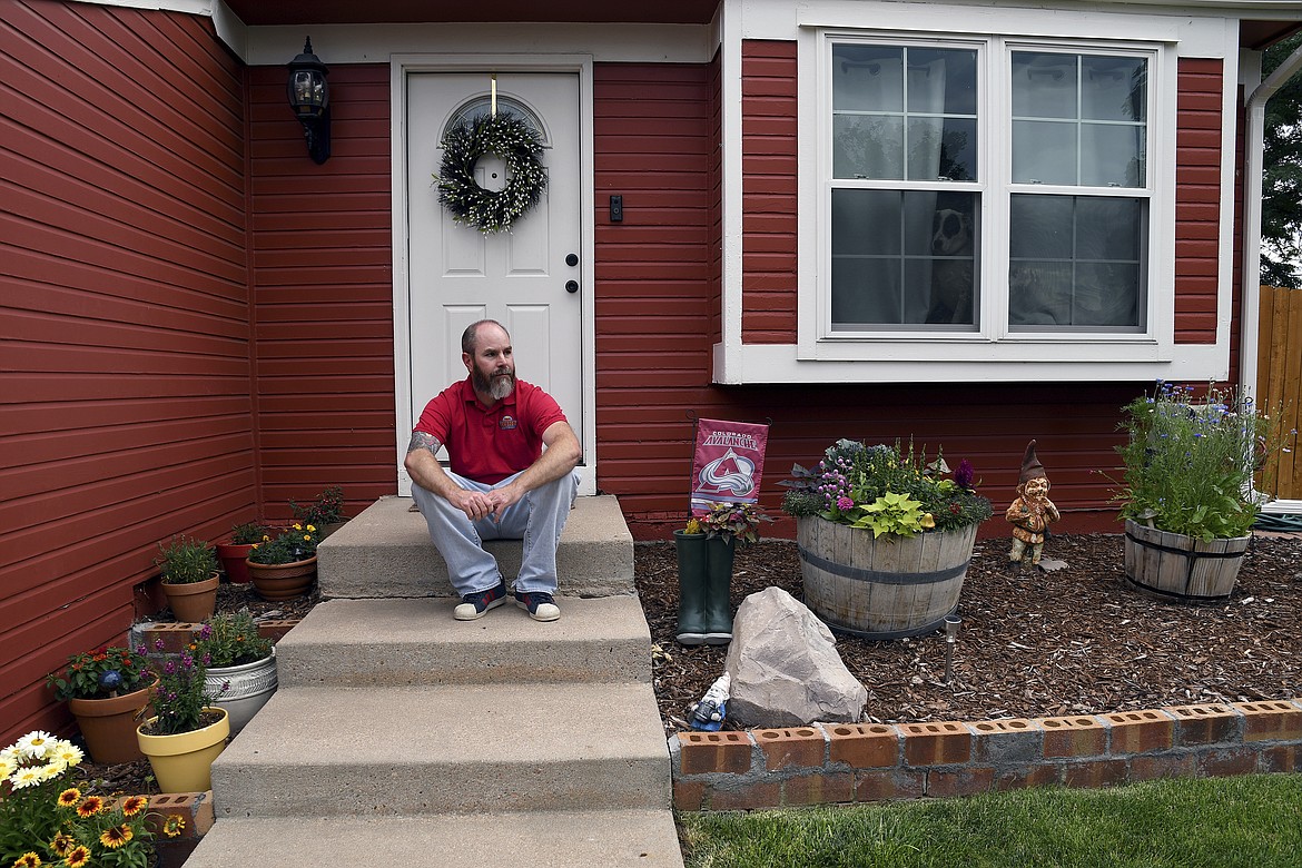 Kyle Tomcak sits in front of his house in Aurora, Colo., on Monday, July 18, 2022. Tomcak was in the market for a home priced around $450,000 for his in-laws and he and his wife bid on every house they toured, regardless of whether they fell in love with the home. He said his search became increasingly dispiriting as he not only lost out to investors fronting cash offers $100,000 over asking price but as mortgage rates started to balloon. He has since pulled out of the housing search. (AP Photo/Thomas Peipert)