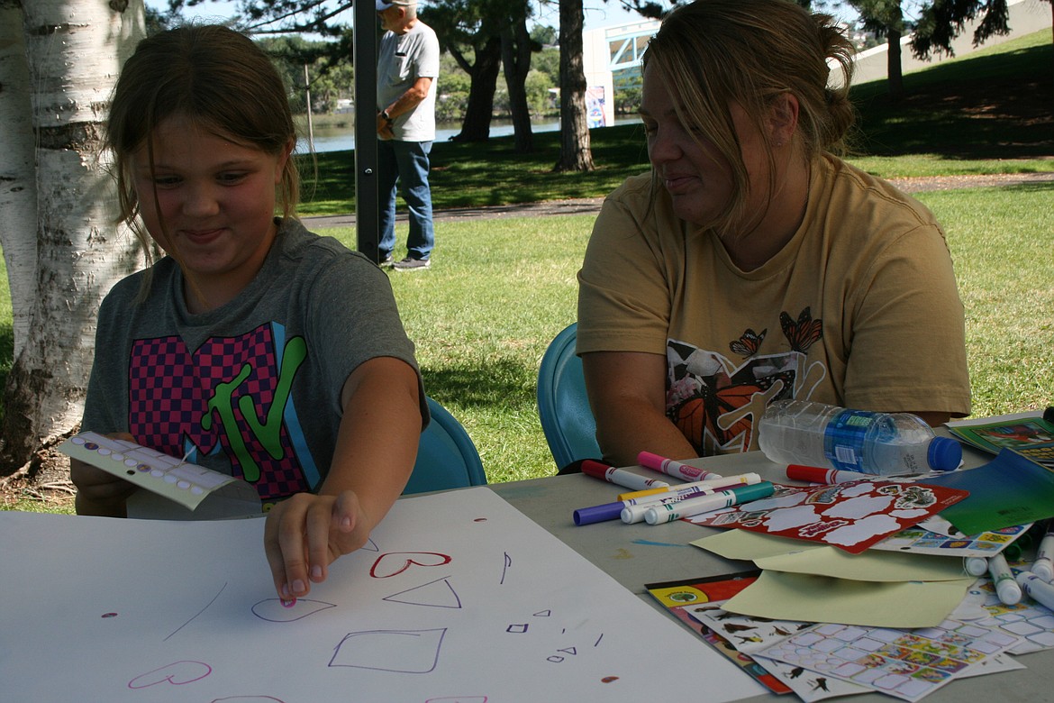 Paisleigh Rippert adds stickers to her giant paper airplane while her mom Lindsey Rippert watches.