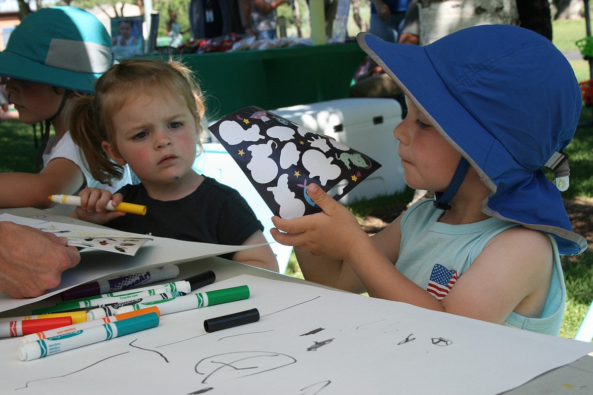 Under the watchful eye of his sister Thea Stoker (left), Joel Stoker (right) chooses a sticker for his giant paper airplane.