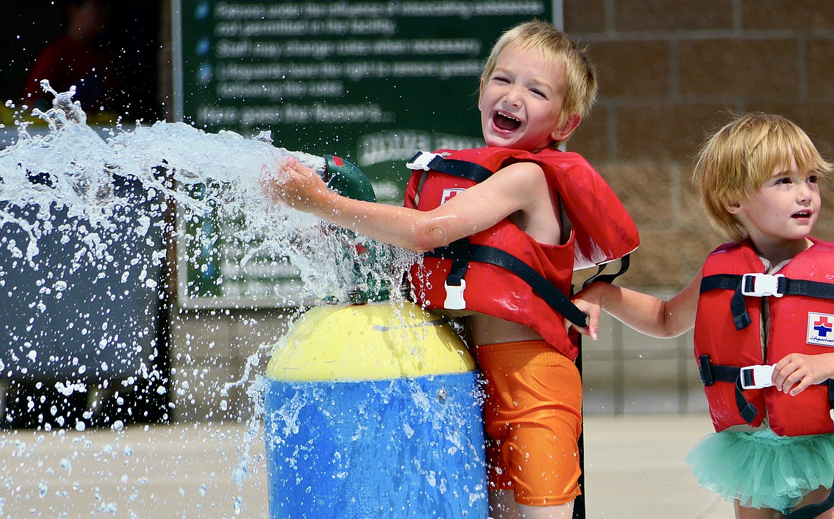 Frankie, 5, and Evelyn Nelson, 4, cool off at the splash pad at Woodland Park in Kalispell on Thursday, July 21. Sunny skies with highs in the 80s and lows in the 50s are predicted through the next week. (Matt Baldwin/Daily Inter Lake)