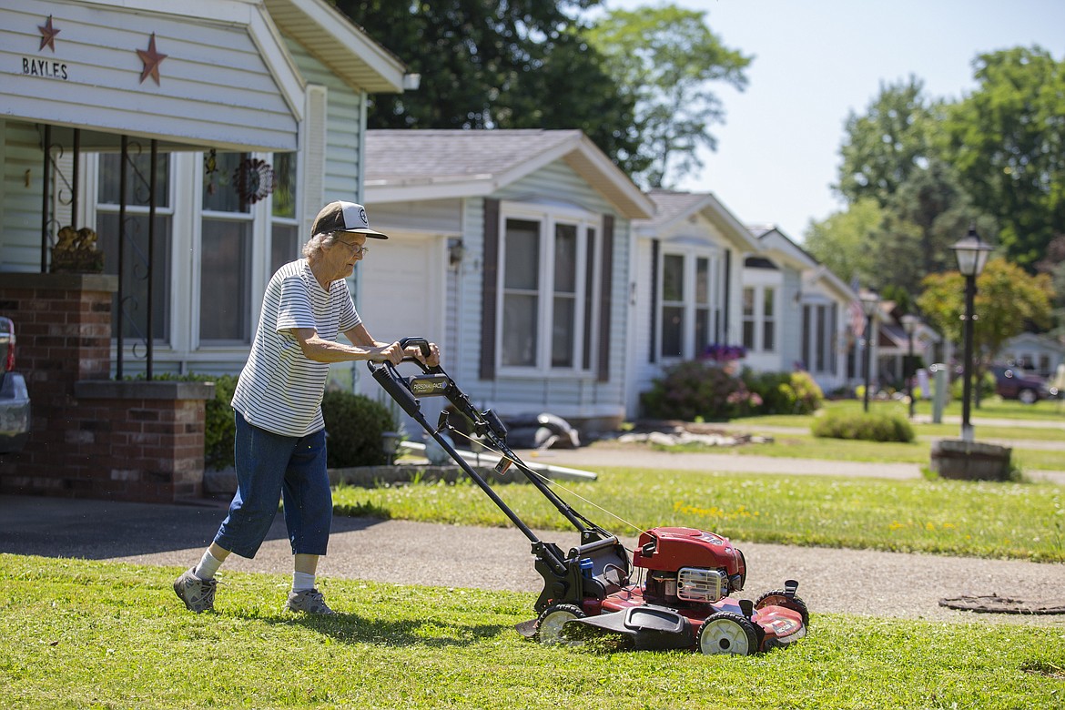 Joyce Bayles, 85, mows the lawn around her home in the Ridgeview Homes mobile home community in Lockport, N.Y. , June 23, 2022. The 85-year-old resident has taken to mowing her own lawn because crews for Ridgeview show up only monthly. Bayles is not participating in a rent strike with other residents of Ridgeview and doesn't want to get involved. "They're going to raise the rent and there's nothing I can do about it," said Bayles. (AP Photo/Lauren Petracca)