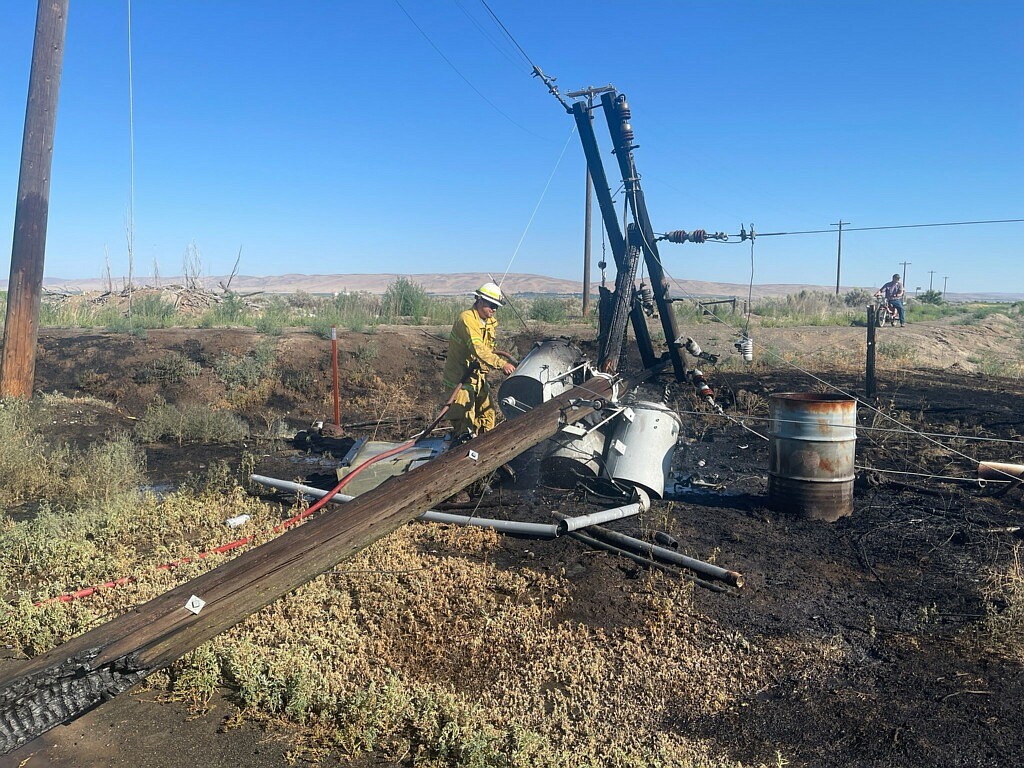 Grant County Fire District 13 Battalion Chief Casey McDonnell works to ensure the fire is out on the utility pole that caught fire Monday morning just south of Ephrata.