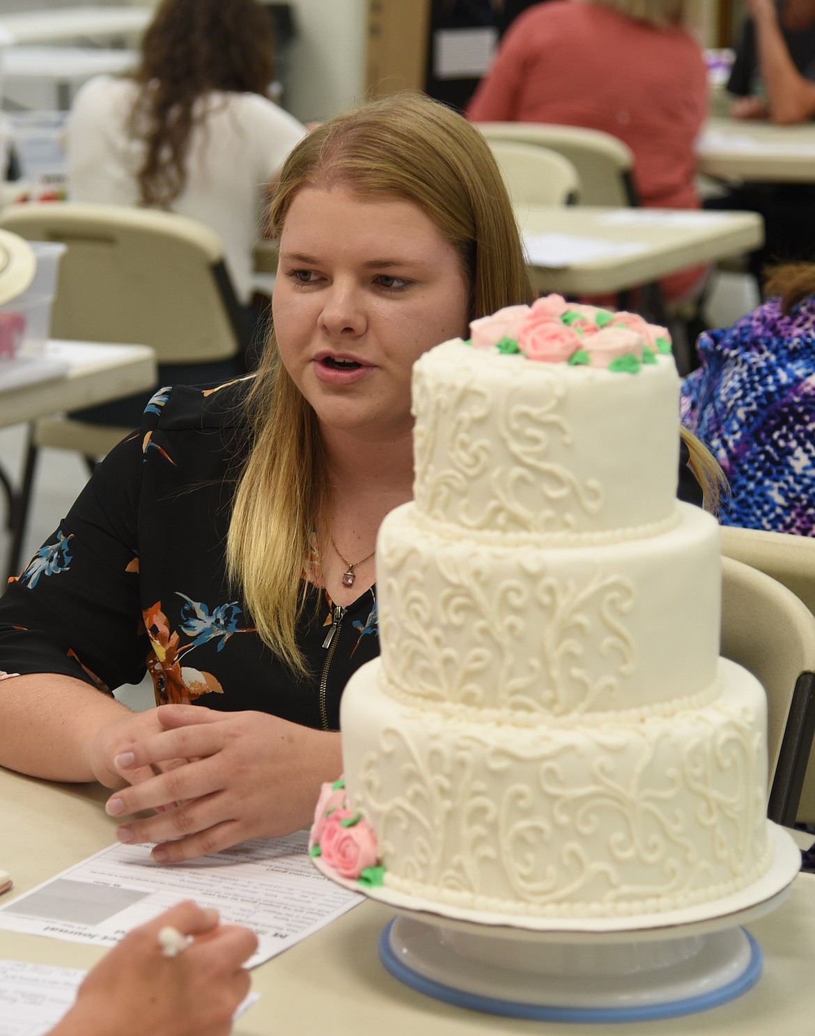 Kiara Sherman talks with a judge about her beautifully decorated wedding cake. This talented 2022 graduate will have entries in a number of wide ranging categories from sewing to market beef. if past performances are good indicators she is likely to walk away with several purpple ribbons and perhaps some Grand Champion Awards as well. (Marla Hall/For the Leader)