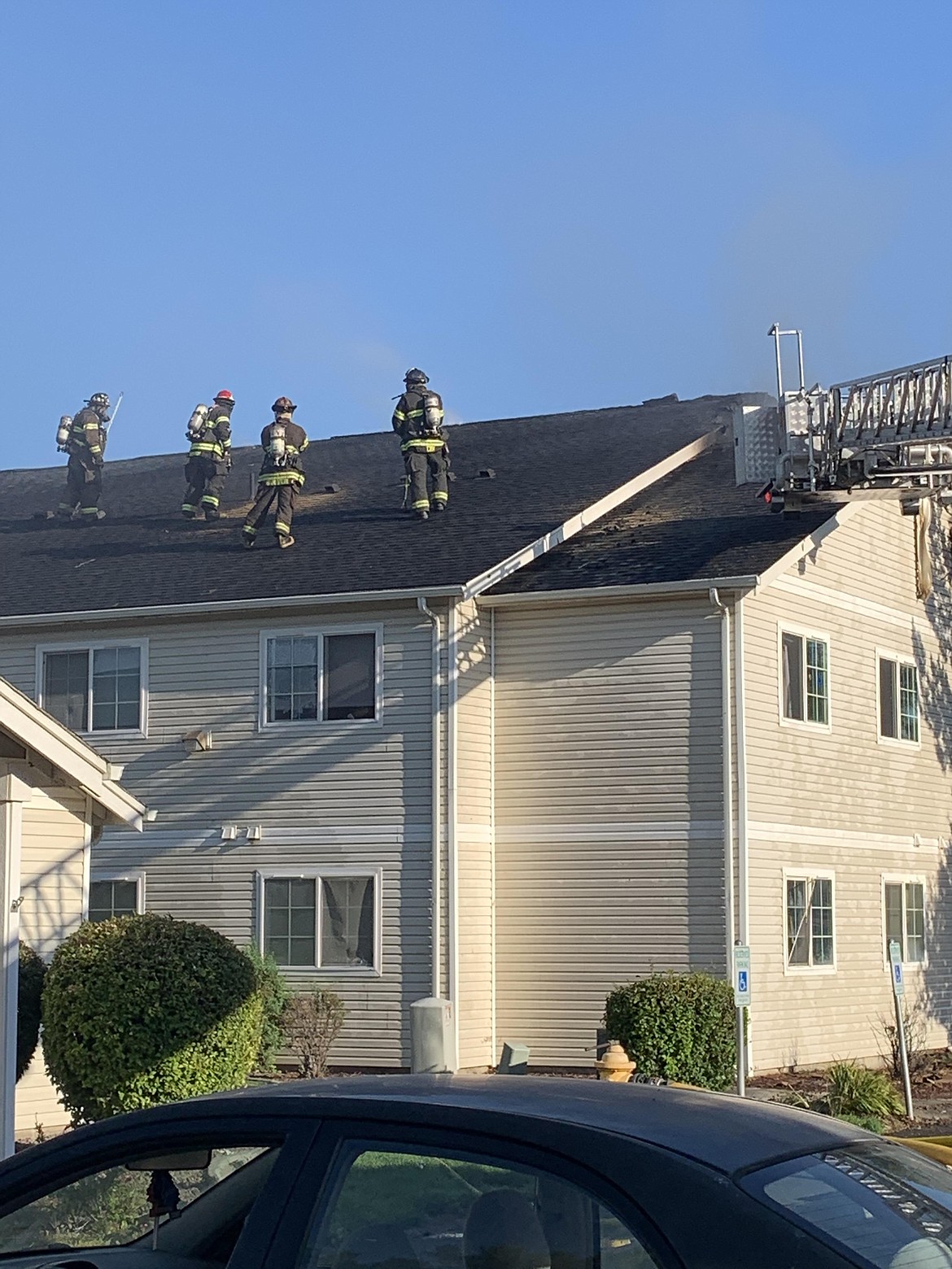 Grant County Fire District 3 firefighters climb the roof to fight a fire at a Quincy apartment building Monday afternoon.