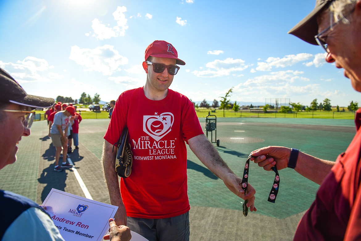 Derek Ball receives a certificate and an award from Jennifer Johnson and Dan Johns after a Miracle League of Northwest Montana game between the Angels Grey and Pirates at Kidsports Complex on Tuesday, July 26. (Casey Kreider/Daily Inter Lake)