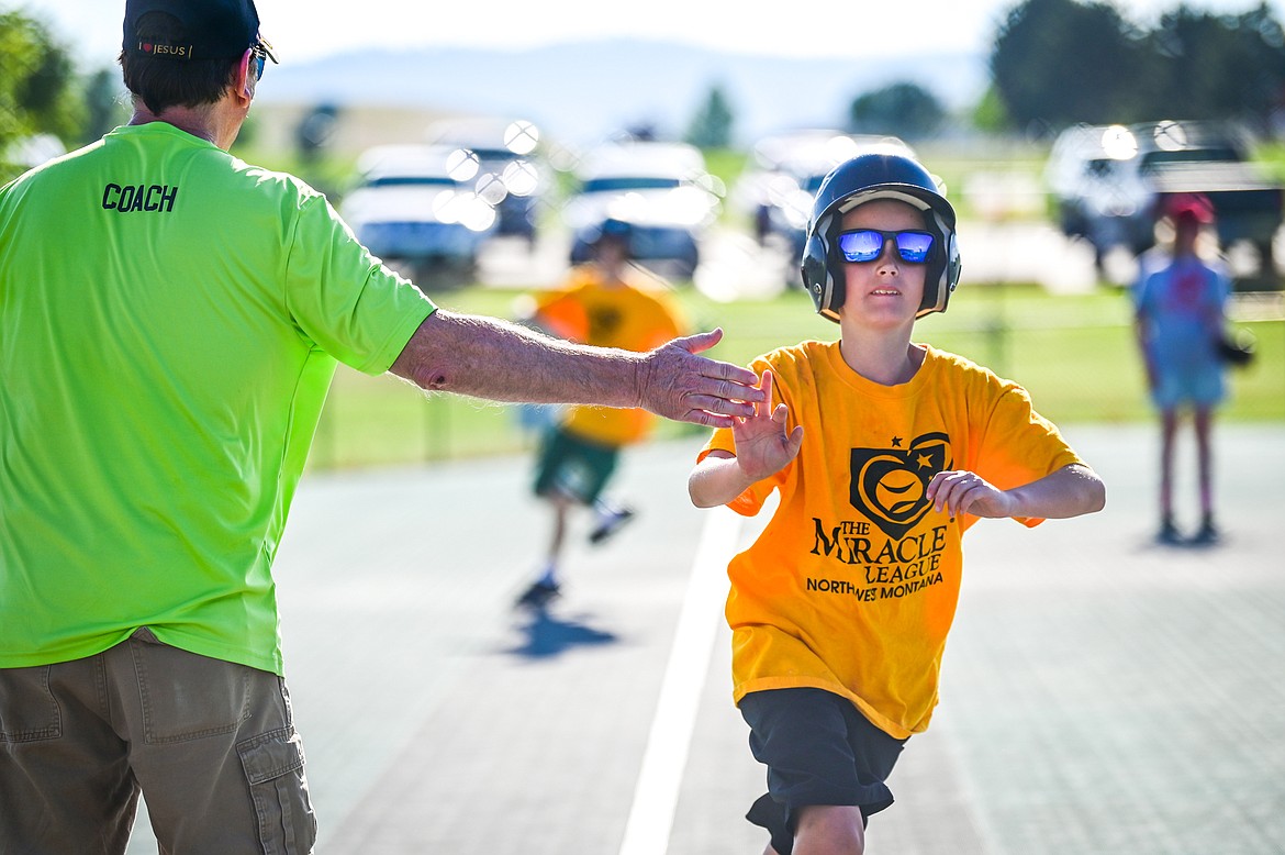 Ryley Shiell of the Pirates gets a high five from coach, catcher and volunteer Rick Heitz as he crosses home plate during a Miracle League of Northwest Montana game against the Angels Grey at Kidsports Complex on Tuesday, July 27. (Casey Kreider/Daily Inter Lake)