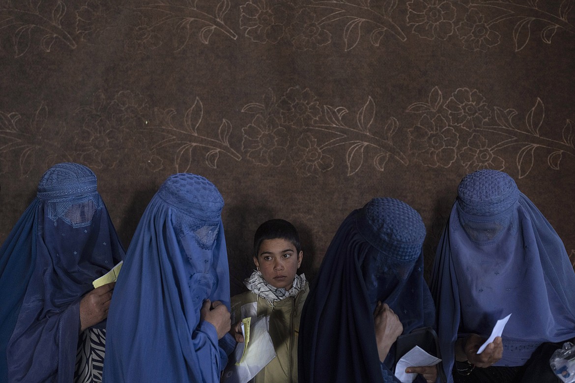 Afghan women wait to receive cash at a money distribution point organized by the World Food Program, in Kabul, Afghanistan, on Nov. 20, 2021. The lives of Afghan women and girls are being destroyed by the Taliban’s crackdown on their human rights, said Amnesty International in a new report Wednesday, July 27, 2022. The London-based watchdog criticized Taliban authorities saying that since Taliban took control of the country in August 2021, they have violated women’s and girls’ rights to education, work and free movement. (AP Photo/Petros Giannakouris, File)