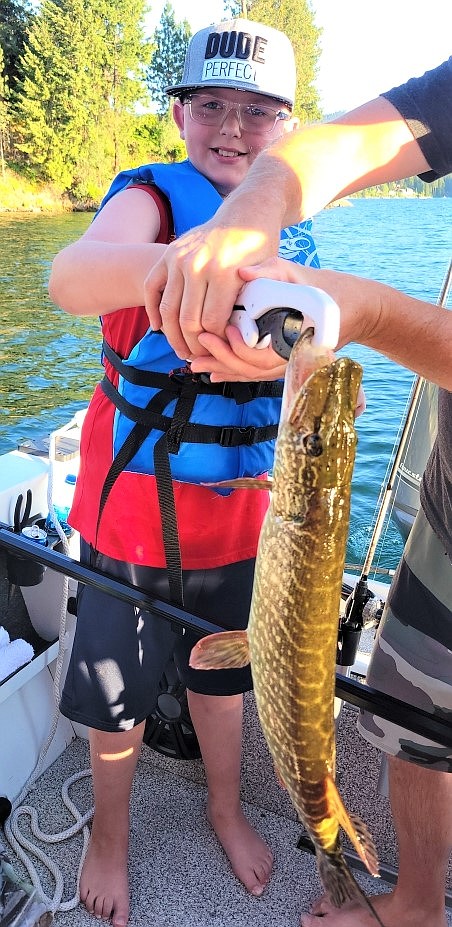 Tucker Inman-Melius, 10, shows off a big pike he recently pulled from Hayden Lake. He is joined by his uncle Levi Peterson, center, and his father, Ben Melius. The fish weighed about 20 pounds.