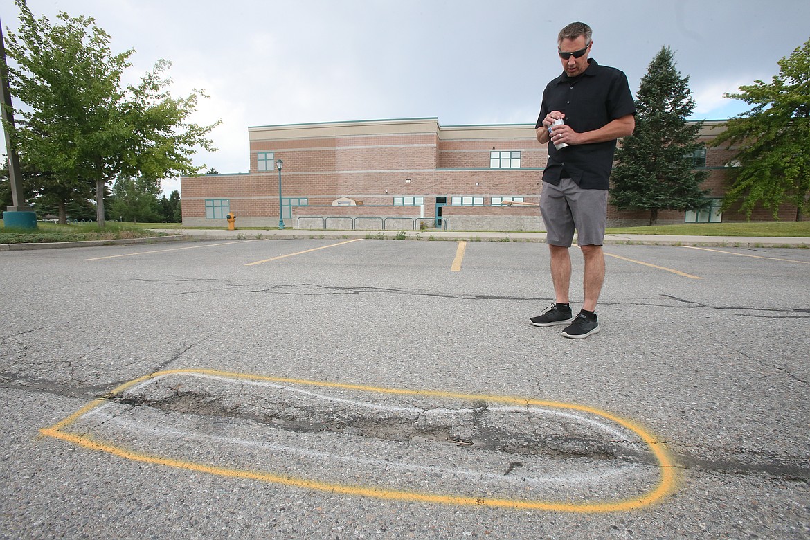 Jeff Voeller, director of operations for the Coeur d'Alene School District, points out one of several potholes highlighted with yellow spray paint in the Lake City High School parking lot.