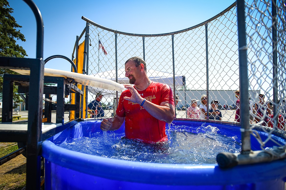 Flathead County Sheriff Brian Heino smiles and fixes the seat after splashing into the dunk tank at the Knights of Columbus Brisket Showdown at the Flathead County Fairgrounds on Saturday, July 30. (Casey Kreider/Daily Inter Lake)