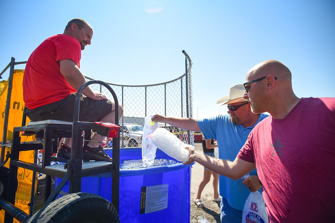 At right, Charles Pesola, a deputy with the Flathead County Sheriff's Office, and Sam Nunnally, manager of the Flathead County Fairgrounds, pour bags of ice into the water as Flathead County Sheriff Brian Heino gets ready for his turn in the dunk tank at the Knights of Columbus Brisket Showdown at the Flathead County Fairgrounds on Saturday, July 30. (Casey Kreider/Daily Inter Lake)