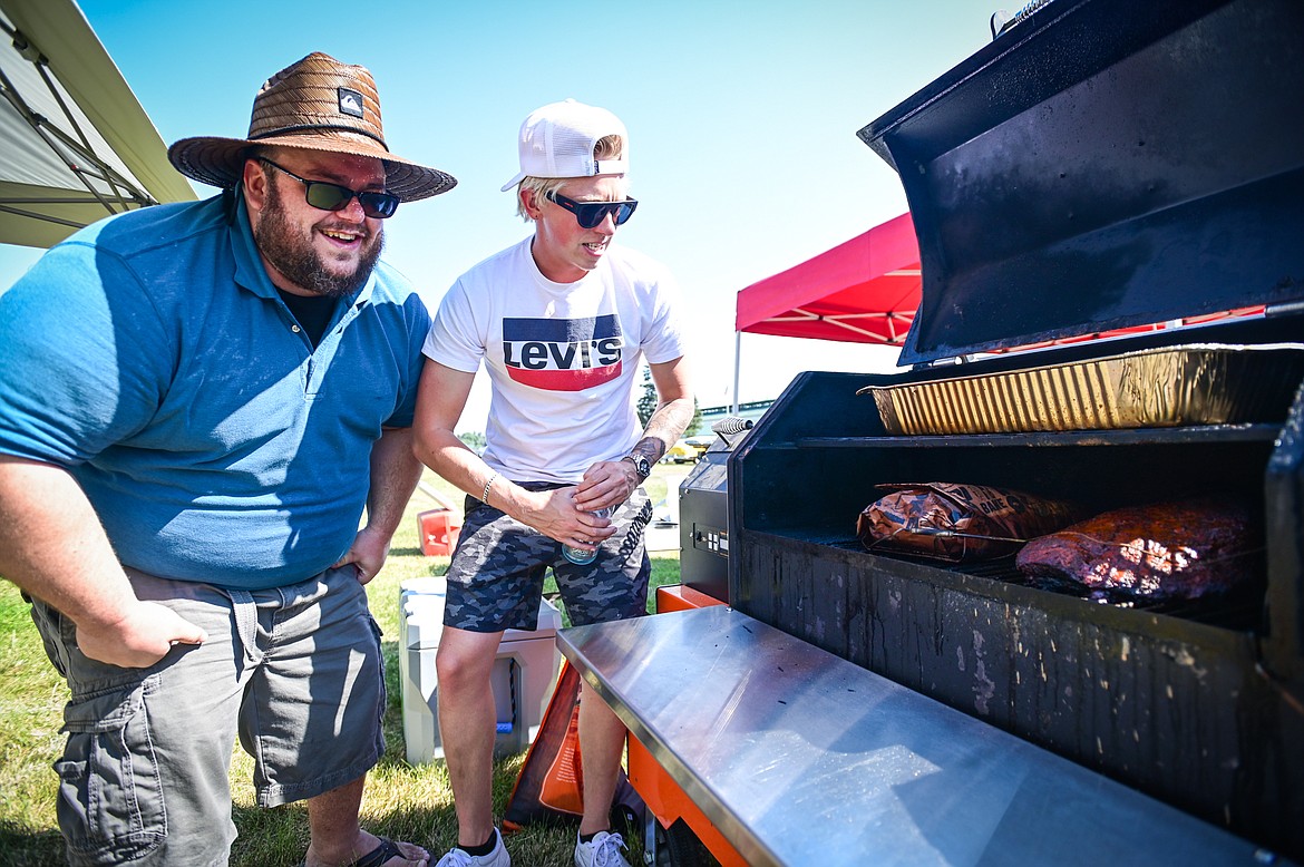 Cale Greene and Cayden Roberson, with the team Great Northern Barbeque, check on their brisket on their Yoder Smoker  at the Knights of Columbus Brisket Showdown at the Flathead County Fairgrounds on Saturday, July 30. (Casey Kreider/Daily Inter Lake)