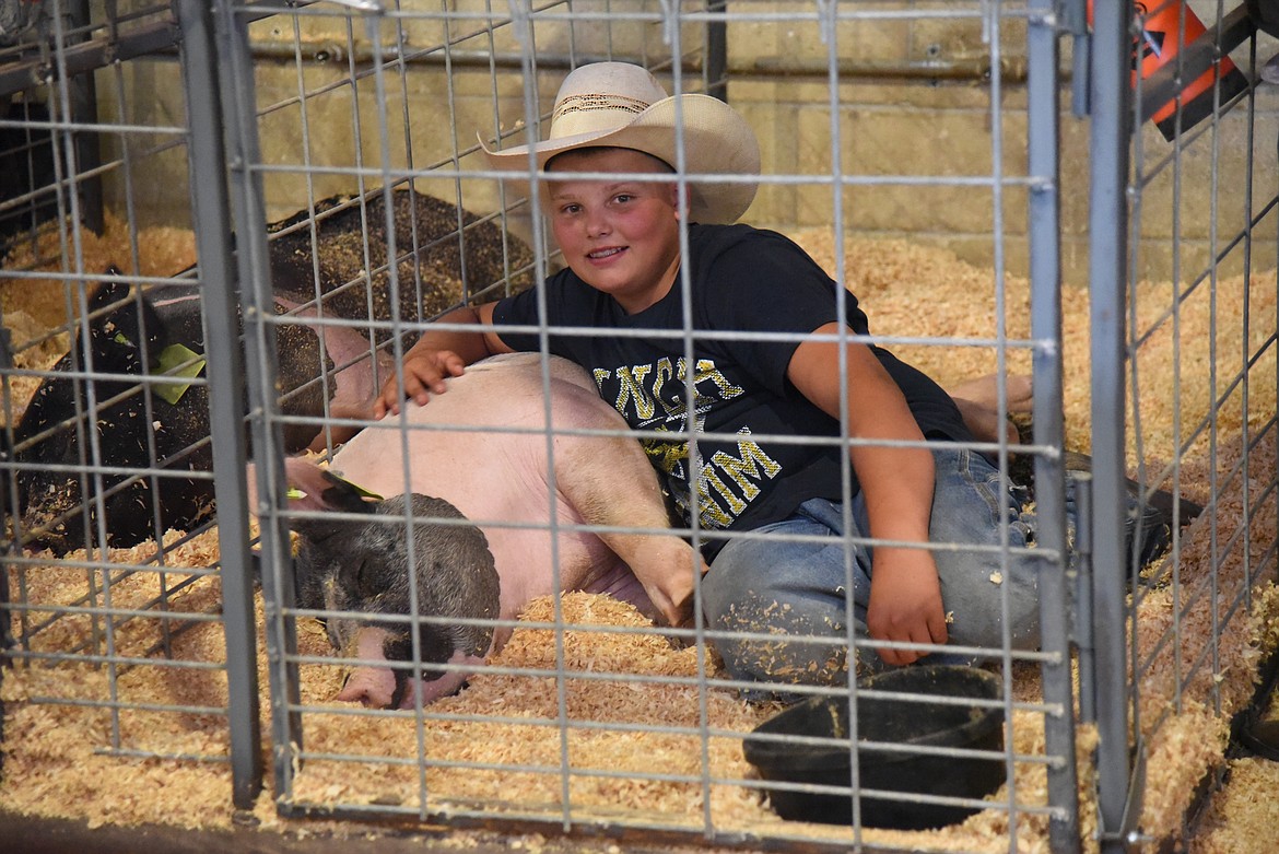 Cooper Raymond relaxes with his hog afters showing the animal in the market hog competition at the Lake County Fair. (Marla Hall/Lake County Leader)