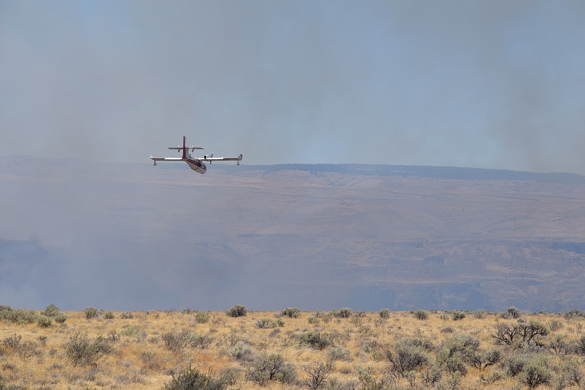 A firefighting airplane takes a run over the Columbia River near Frenchman Coulee early Tuesday afternoon. The fire has burned an estimated 8,000 acres so far and firefighting agencies from across the state have been activated to fight the blaze.