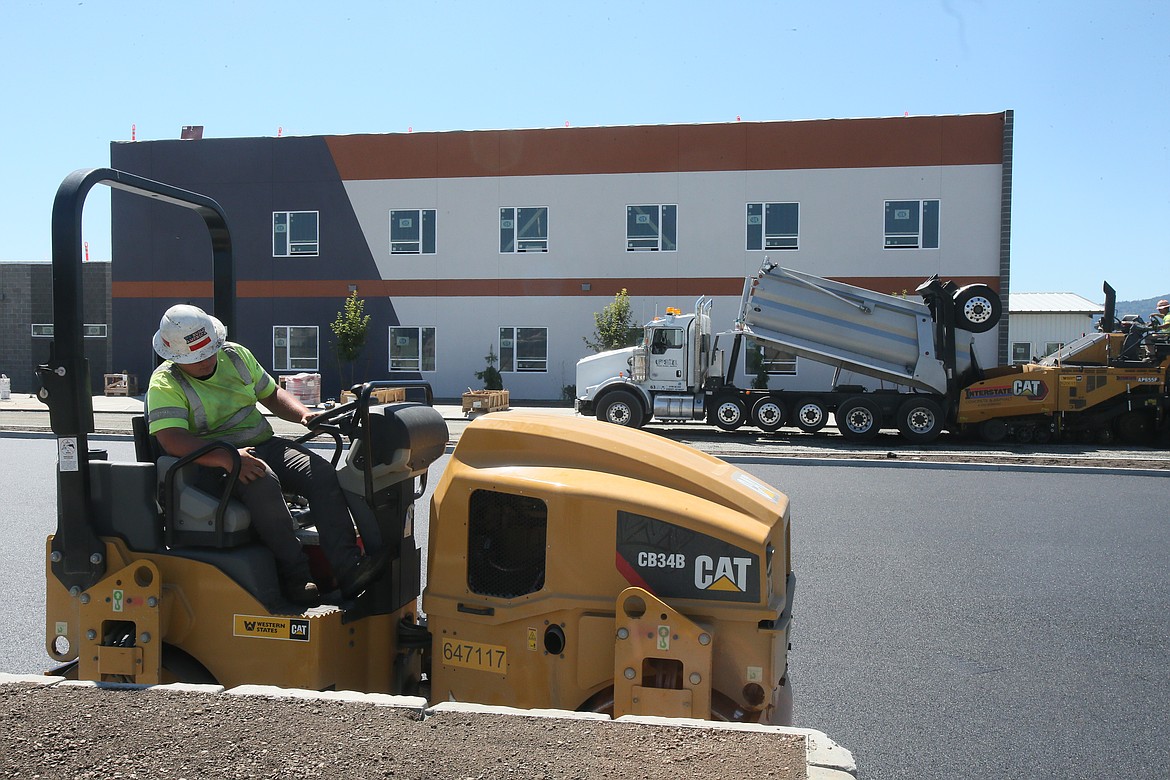 Workers move dirt and pave the parking lot at the career technical public charter school Elevate Academy North on July 19.