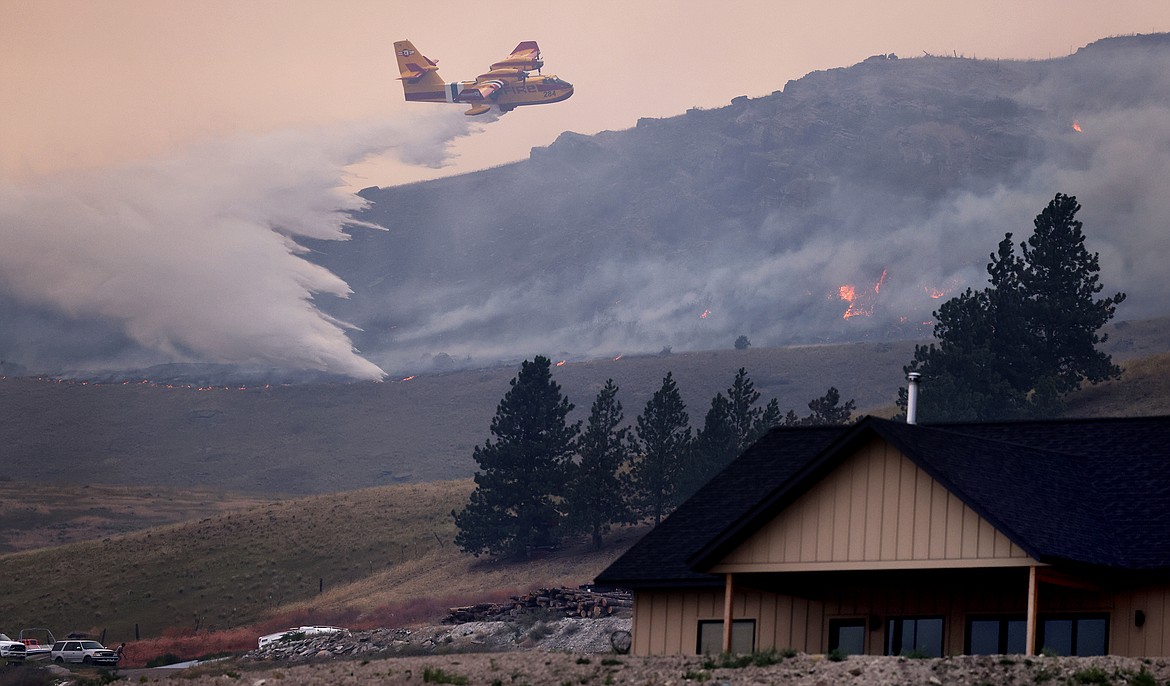 A Bridger Aerospace CL-415EAF super scooper dumps water in an attempt to stop the Elmo Fire from approaching a house along U.S. 93 Monday afternoon, Aug. 1. (Jeremy Weber/Daily Inter Lake)