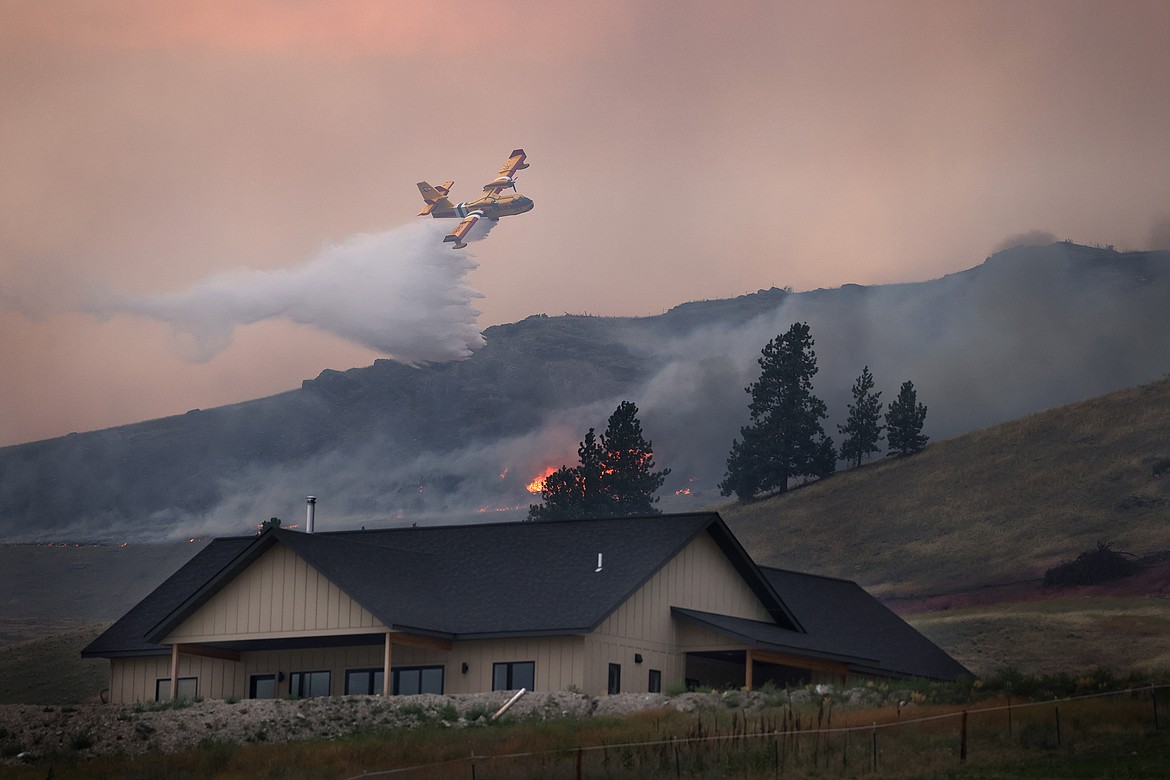 A CL-415EAF super scooper dumps water in an attempt to stop the Elmo Fire from approaching a house along U.S. 93 Monday afternoon, Aug. 1. (Jeremy Weber/Daily Inter Lake)