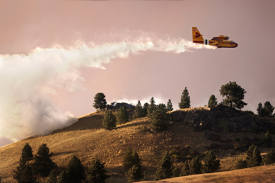 A CL-415EAF super scooper dumps water in an attempt to stop the Elmo Fire from approaching houses along U.S. 93 Monday afternoon, Aug. 1. (Jeremy Weber/Daily Inter Lake)