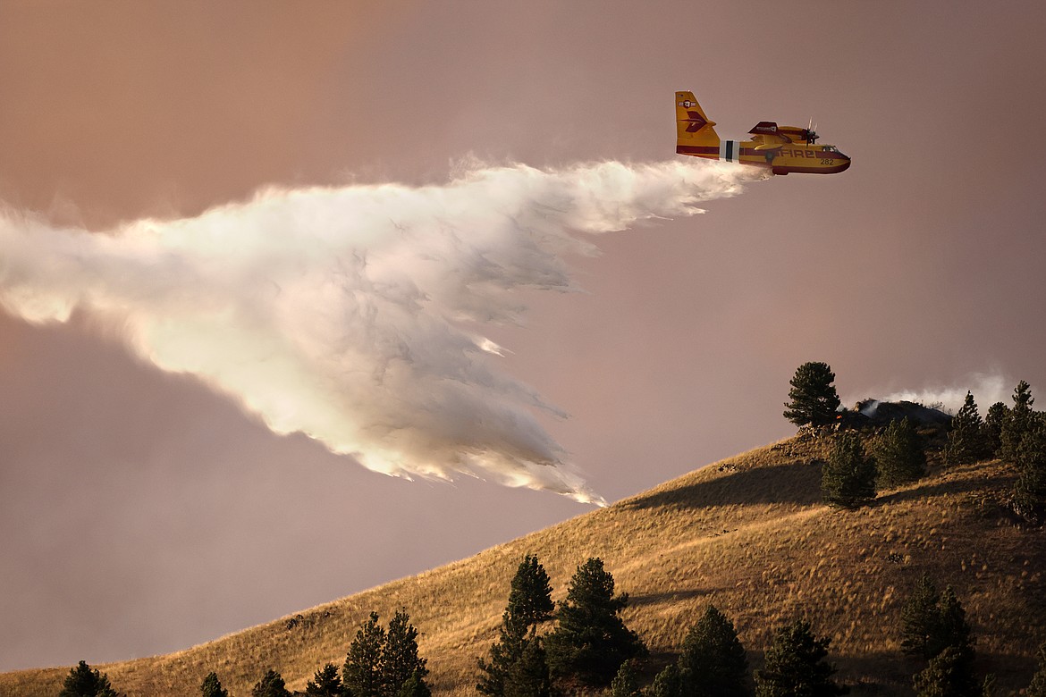 A CL-415EAF super scooper dumps water in an attempt to stop the Elmo Fire from approaching houses along U.S. 93 Monday afternoon, Aug. 1. (Jeremy Weber/Daily Inter Lake)