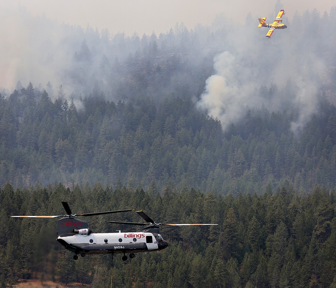 A Billings Flying Service CH-47D helicopter collects water from Black Lake while a Bridger Aerospace CL-415EAF super scooper drops water on the Elmo Fire Monday, Aug. 1. (Jeremy Weber/Daily Inter Lake)