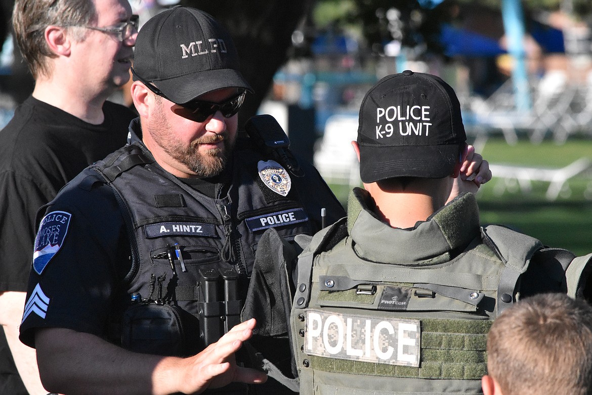 Moses Lake Police Officer Aaron Hintz helps a child try on a vest during the Moses Lake National Night Out. The annual event allows law enforcement and other first responders to get to know the public they serve in a lower.