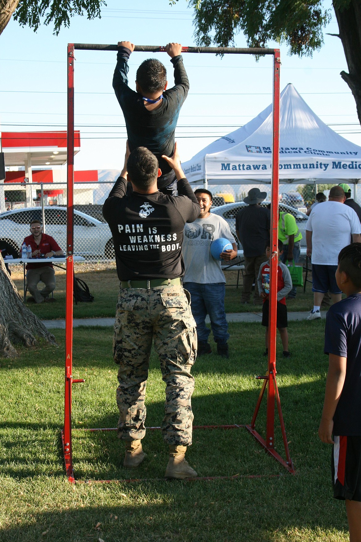 A U.S. Marine gives a hand to a child trying out the chinup bar.