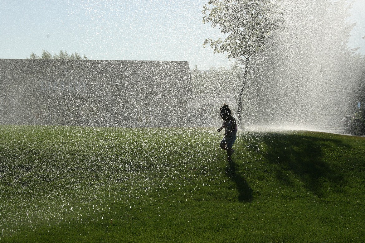 Maryana Martinez runs through the fountain of water supplied by Grant County Fire District 8 during National Night Out in Mattawa.