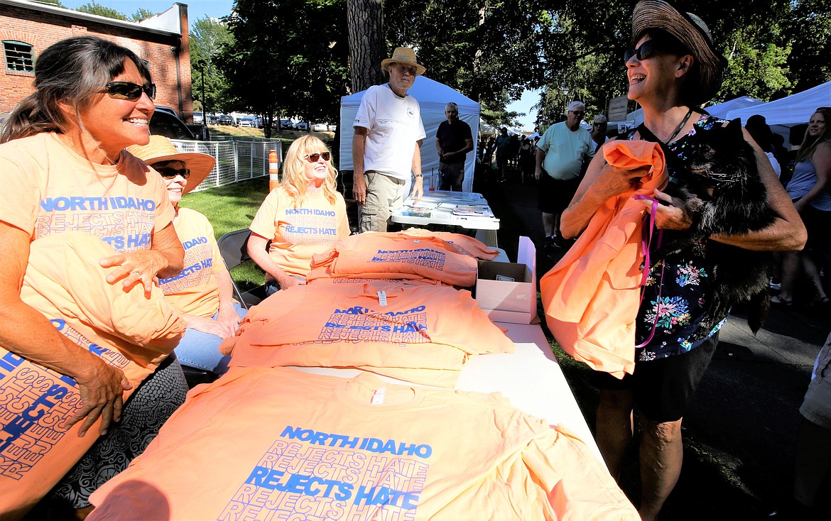 Cindy Little of Hayden, holding Bella, receives a "North Idaho Rejects Hate" shirt from Tere Porcarelli, Mary Ann Landers and Christie Wood at City Park, where Taste of Coeur d'Alene was taking place Friday.