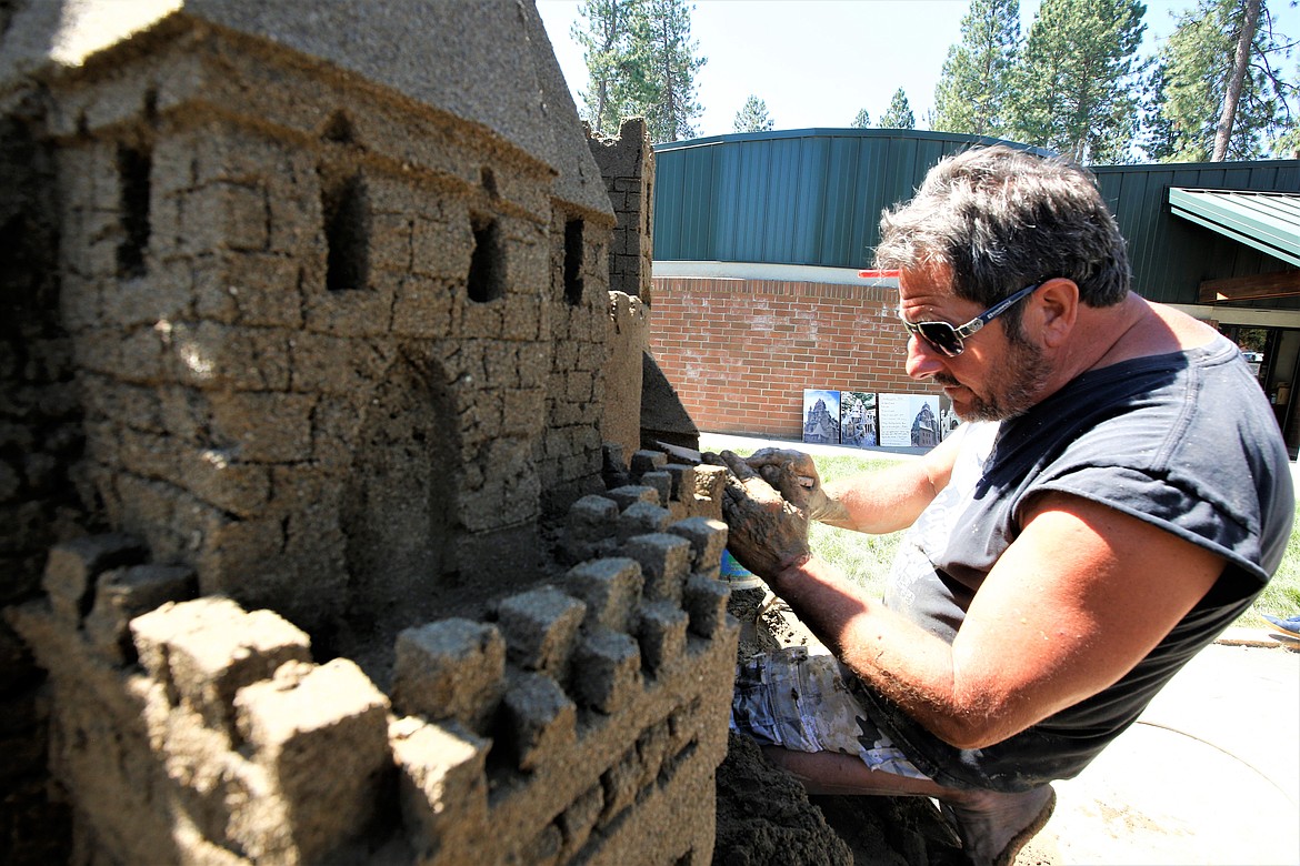 Scott Dodson works on a sandcastle at Art on the Green on Friday.