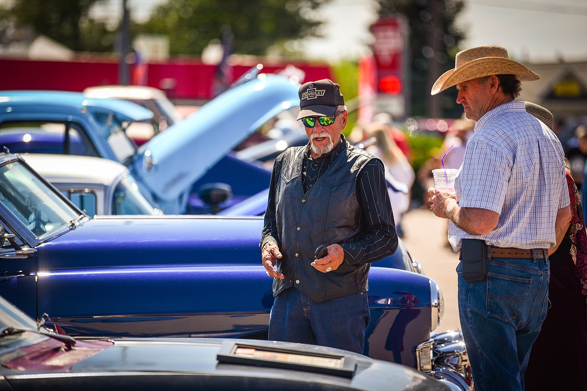 Peter Drowne, left, talks with an attendee about his 1966 Chevy Corvair that features 340 horsepower from a 1965 Corvette engine at the Evergreen Show 'N Shine car show at Conlin's Furniture on Saturday, Aug. 6. (Casey Kreider/Daily Inter Lake)