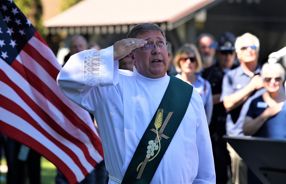 Deacon Andy Finney, a sergeant with the Air Force, salutes during the dedication of the new veterans monument at St. Thomas Cemetery on Sunday.