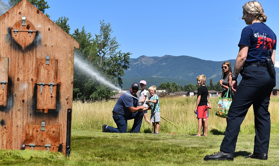 Members of the Whitefish Fire Department help kids practice aiming a firehose at the Kids Fair on Aug. 3. The event was hosted by the Flathead Valley Breastfeeding Coalition. (Julie Engler/Whitefish Pilot)
